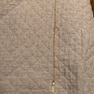 Long gold Kendra Scott necklace with clear crystal on the end